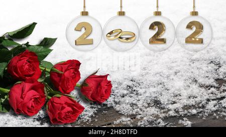 goldene Eheringe in durchsichtiger Glas-weihnachtskugel mit 2022 Ziffern und frischen roten Rosen auf silbernem Lametta-Hintergrund Stockfoto