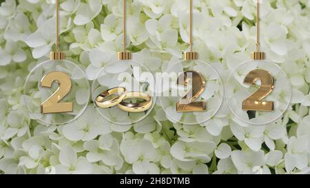 Weiße Hochzeit goldene Ringe in transparentem Glas weihnachtskugel 2022 Ziffern auf weißem Hortensienblüten Hintergrund Stockfoto