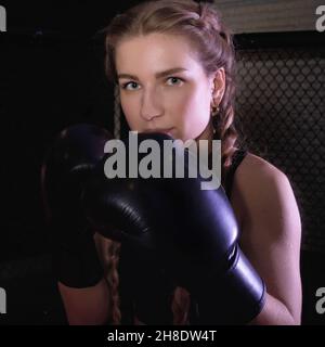Porträt einer jungen Frau in Boxhandschuhen in einer fertigen Pose. Frauen Fitness-Boxen Workout. Stockfoto