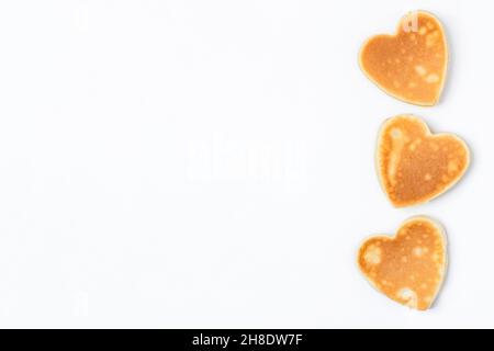 Kreatives Frühstück zum Valentinstag. Herzförmige Pfannkuchen isoliert auf weißem Hintergrund. Valentinstag Hintergrund. Draufsicht. Flach liegend. SPA kopieren Stockfoto