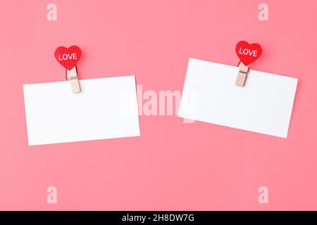 Weiße Notenblätter mit Herzen Wäscheklammern mit Text Liebe, auf einem rosa Hintergrund. Das Konzept des Valentinstag, Liebeserklärung. Speicherplatz kopieren Stockfoto