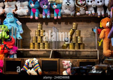 Wurfstand auf dem Weihnachtsmarkt mit Dosen, Ball und bunten Plüschspielzeugen als Preise, ausgewähltem Fokus, Bewegungsunschärfe Stockfoto