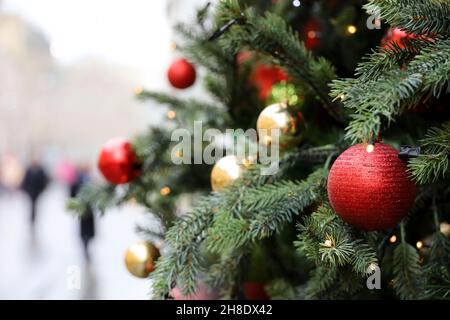 Neujahrsdekoration auf einer Stadtstraße. Weihnachtsbaum mit roten und goldenen Spielzeugkugeln auf unscharfem Hintergrund Stockfoto