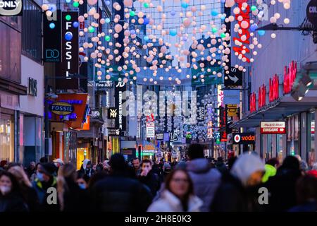 Köln, Deutschland. 29th. November 2021. In der Abenddämmerung laufen die Menschen entlang der Einkaufsstraße hohe Straße. Quelle: Rolf Vennenbernd/dpa/Alamy Live News Stockfoto