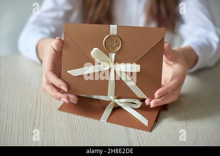 Geschenkgutschein, Geschenkgutschein oder Rabatt. Nahaufnahme des Einladungsumschlags mit Band und Wachssiegel, Geschenkgutschein, Hochzeitseinladungskarte. Stockfoto