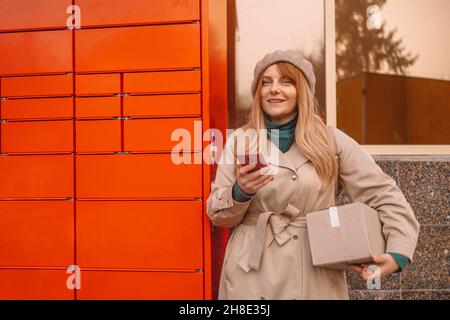 Paket abholen. Frau holt Post vom automatischen Postterminal ab. Postversand Konzept, Qualität Lieferservice. Stockfoto