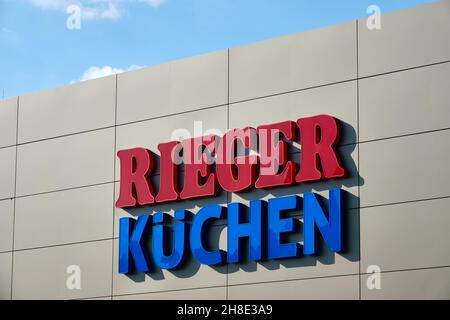 Göppingen, Deutschland - 21. Mai 2020: Küchen Rieger Fasade, blaue und rote Buchstaben, viel Tageslicht mit wolkblauem Himmel .Göppingen. Stockfoto