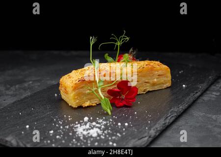 Dauphinua Kartoffelgratin mit Kirschtomaten auf schwarzem Stein Stockfoto