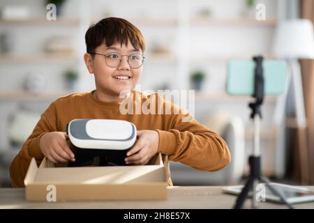 Fröhlicher asiatischer Teenager, der von zu Hause aus per Handy streamt Stockfoto