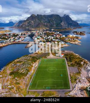 Luftaufnahme des Fußballfeldes oder Fußballfeldes im Henningsvaer mit Bergen im Hintergrund. Keine Leute, Sommer. Lofoten Islands, Norwegen. Europa Stockfoto