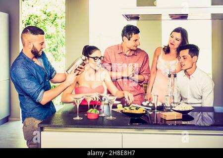 Eine Gruppe von Freunden, die sich auf der Hausparty mit Aperitif-Cocktails und Snacks amüsieren - Junge Menschen verbringen zu Hause Zeit miteinander Stockfoto