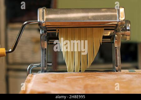 Pasta-Maschine zum Zubereiten von Spaghetti, Nahaufnahme. Hausgemachte Eiernudeln, italienische Küche. Stockfoto