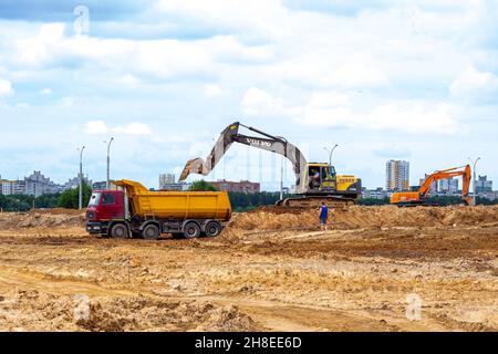 MINSK, WEISSRUSSLAND - 2. Juli 2021: Schwerer Industriebagger in hellgelb, der auf der Baustelle in der Stadt arbeitet. Stockfoto