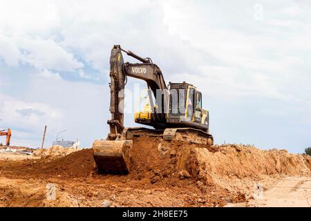 MINSK, WEISSRUSSLAND - 2. Juli 2021: Schwerer Industriebagger in hellgelb, der auf der Baustelle in der Stadt arbeitet. Stockfoto