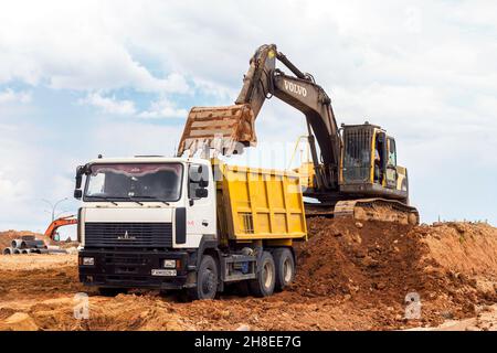 MINSK, WEISSRUSSLAND - 2. Juli 2021: Schwerer Industriebagger in hellgelb, der auf der Baustelle in der Stadt arbeitet. Stockfoto