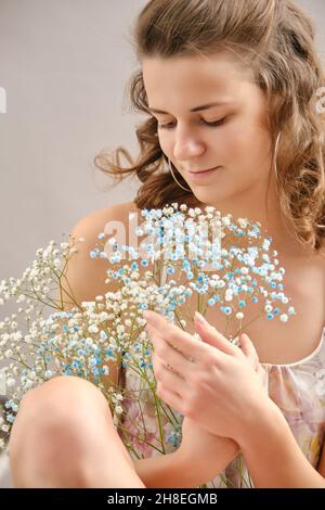 Junge glückliche Frau in Kleid posiert mit Blumen lächeln Stockfoto