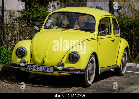 Bukarest, Rumänien, 2. April 2021 Alter gelber Volkswagen Beetle Oldtimer im Retro-Gelb parkte an einem sonnigen Frühlingstag eine Straße Stockfoto