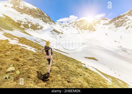 Schweizerin am vereisten See namens Lej Muraglat am Ende der Bergtour auf dem Schneepfad auf dem Berg Muottas Muragl. Schweiz Stockfoto