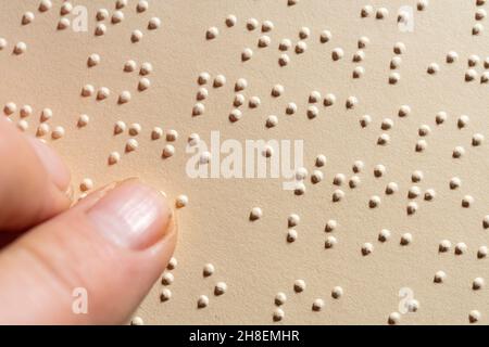 Ein Finger, der dem Lesen einer im Braille-Alphabet geschriebenen Seite folgt, dem taktilen Lesesystem zur Erleichterung für Blinde Stockfoto