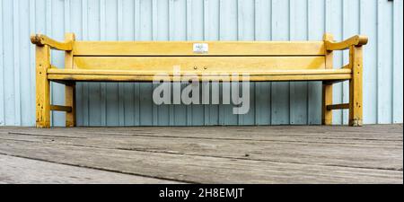 Smögen, Schweden -10. Juni 2021: Holzbank in natürlichen Farben an der Wand mit blauer Holzfassade platziert Stockfoto