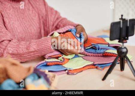 Nahaufnahme einer jungen afroamerikanischen Frau, die zu Hause strickt und Video- oder Livestream-Aufnahmen, Kopierbereich macht Stockfoto