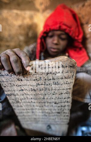 Der junge Mann in einer Koranschule sitzt vor Holztafeln und rezitiert Stunden für Stunde Tag in Timbuktu, Mali, Westafrika, koranische Verse. Stockfoto