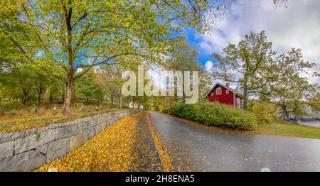 Stockholm, Schweden, 6. Oktober 2021: Schöner Vorort mit Gehwegen, die mit Blättern in Herbstfarbe bedeckt sind Stockfoto