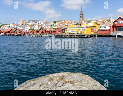 Fjällbacka, Schweden -9. Juni 2021: Farbenfrohe Gebäude an der Bucht an der Westküste Schwedens mit Holzdetails im Vordergrund Stockfoto