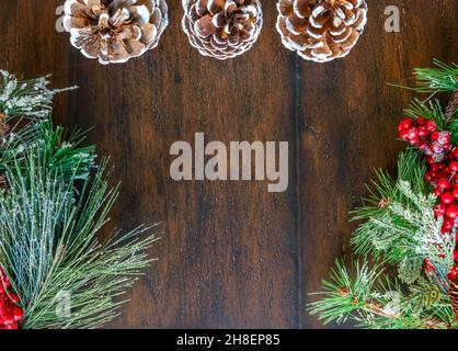 Bild von drei weißen Tannenzapfen mit Tannenzweigen und Beeren auf jeder Seite Stockfoto