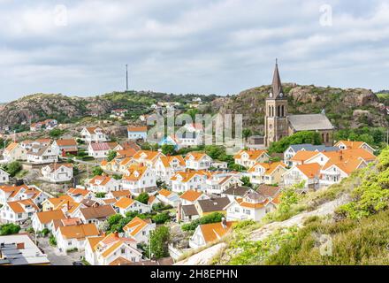 Fjällbacka, Schweden - 9. Juni 2021: Blick vom Hügel auf die kleine schwedische Stadt mit ihren bunten Gebäuden und der alten Kirche Stockfoto