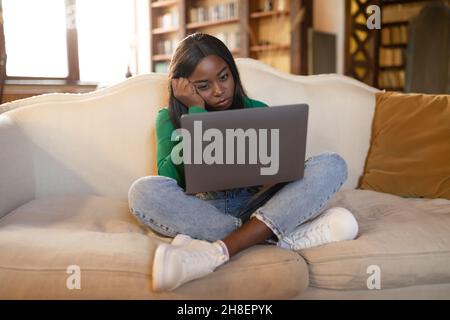 Freiberuflicher Stress. Junge schwarze Frau, die sich müde fühlt, am Laptop arbeitet und Probleme mit Online-Projekten zu Hause hat Stockfoto