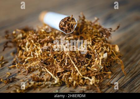 Schneiden Sie Tabakblätter und handgefertigte Zigaretten auf einem hölzernen Hintergrund Stockfoto