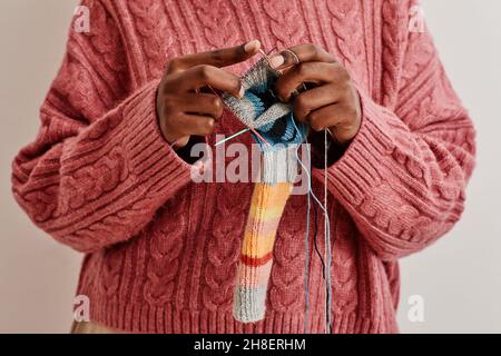 Minimale Nahaufnahme einer jungen afroamerikanischen Frau, die Socken strickt, Kopierraum Stockfoto