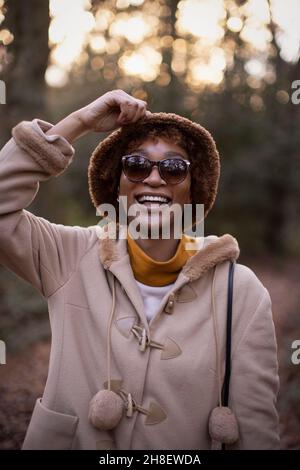 Portrait glückliche junge Frau in Mantel und Hut im Herbstpark Stockfoto