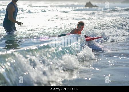 Portrait Happy Boy Body Boarding in sonniger Meeresbrandung Stockfoto