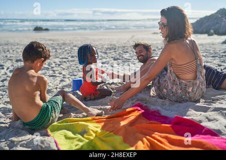 Familie spielt im Sand am sonnigen Sommerstrand