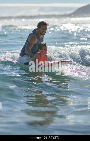 Glücklicher Vater und Sohn boarden in sonnigem Ozean Stockfoto