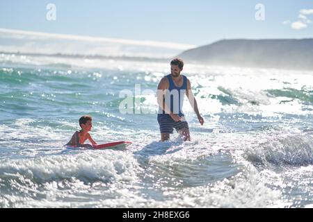 Vater und Sohn boarden im sonnigen Sommer im Meer surfen Stockfoto