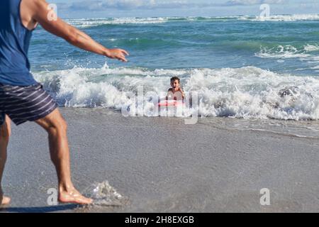 Vater beobachtete glücklichen Sohn Körper beim Boarding in sonnigen Ozean surfen Stockfoto