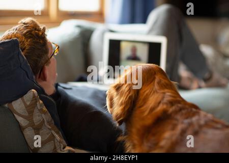 Mann mit Hund Video chattet mit Laptop auf dem Sofa Stockfoto