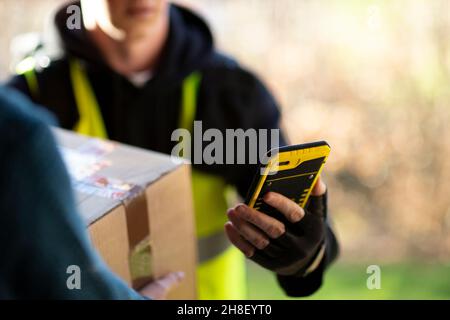 Nahaufnahme Kurier mit Smartphone Lieferung Paket Stockfoto