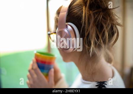 Frau mit Kaffee, die Musik über Kopfhörer hört Stockfoto