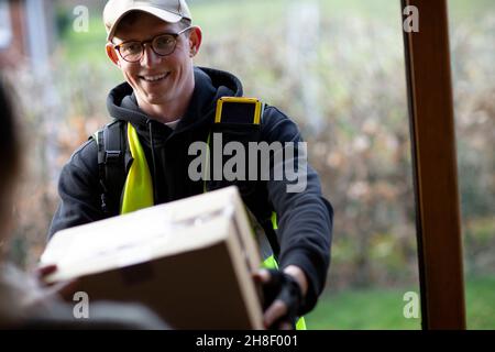 Freundlicher männlicher Kurier, der das Paket vor der Tür lieferte Stockfoto