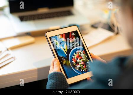 Frau, die auf dem digitalen Tablet das Menü zum Mitnehmen ansieht Stockfoto