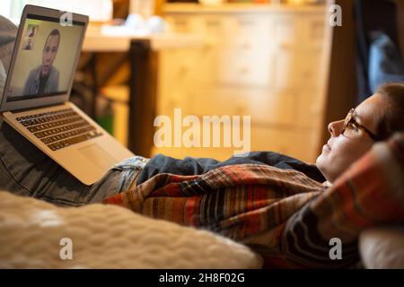 Legere Frau, die von zu Hause aus mit Kollegen auf einem Laptop chattet Stockfoto