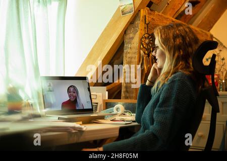 Frau chattet im Heimbüro mit Kollegen auf dem Laptop-Bildschirm Stockfoto