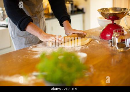 Mann rollt Teig in der Küche aus Stockfoto