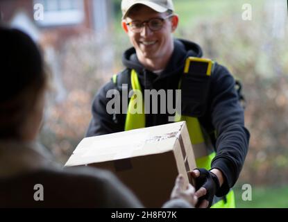 Freundlicher männlicher Kurier, der das Paket vor der Tür lieferte Stockfoto