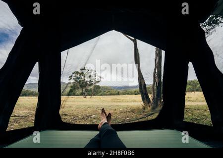 POV-Frau, die sich im Zelt im abgelegenen australischen Busch entspannt Stockfoto