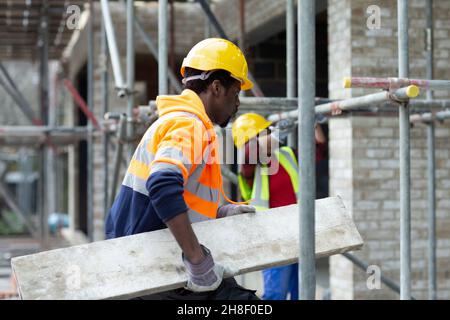 Bauarbeiter, der Holz auf der Baustelle transportiert Stockfoto